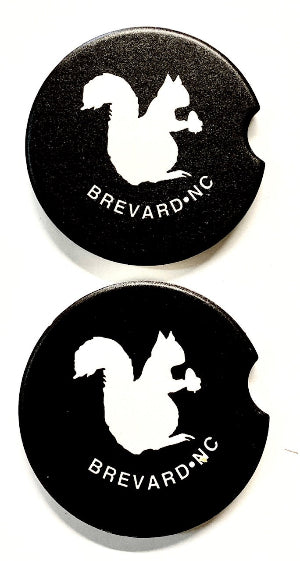 Two black car coasters with a white squirrel design and 'Brevard, NC' text.