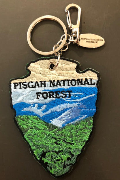 Embroidered key chain in the shape of an arrowhead with a mountain scene and 'Pisgah National Forest' on it.