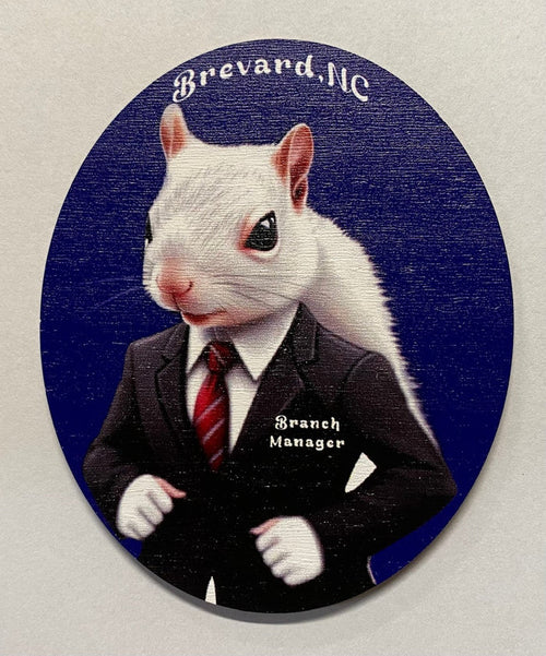 A magnet featuring a cartoon image of a white squirrel dressed in a business suit with the title 'Branch Manager' on the chest, set against an oval blue background with the text 'Brevard, NC'.